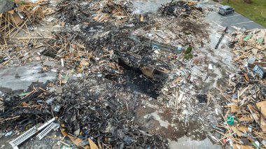 Yoldaki arabalarla ve bulutlu bir gökyüzünün altındaki yeşil alanlarla çevrili yıkık dökük bir binanın hava görüntüsü..