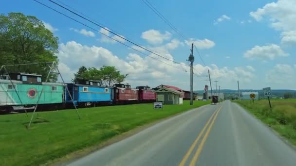 ロンクス ペンシルベニア 2022年5月22日 静止した列車の車の活気に満ちたコレクションで国道を下り その横にアミッシュ馬とバギーを通り過ぎる — ストック動画