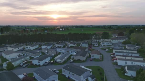 当太阳下山的时候 一个宁静的郊区在昏暗的天空下沐浴着 给整齐排列的移动房屋 预制房屋 提供了温暖的光芒 — 图库视频影像