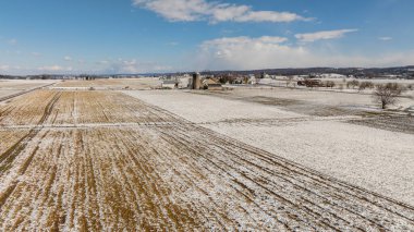 An Aerial View Of Snow-Speckled Agricultural Fields And Farm Buildings. clipart