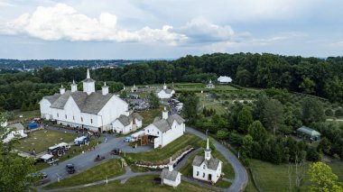 Elizabethtown, Pennsylvania, ABD, 4 Temmuz 2024 - Beyaz binalı, yemyeşil, yuvarlak tepeler ve ağaç kümeleri arasında geçen, içinde bir kilise ve ahır bulunan kırsal bir manzara