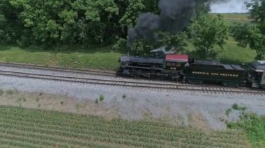 Ronks, Pennsylvania, ABD, 27 Mayıs 2022 - Bir Norfolk ve Batı Buharlı Trenin Yeşil Tarlalar, Ağaçlar ve temiz bir gökyüzü eşliğinde tarlalarda dolaşırken yoğun siyah dumanlar saçması