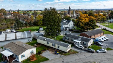 Çeşitli Mobil, Prefabrik, Üretilmiş evler renkli sonbahar ağaçları ve uzak bir sanayi bölgesi olan kırsal bir ortamda görülür..