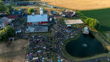 Ronks, Pennsylvania, ABD, 3 Temmuz 2024 - Büyük bir kalabalık, Red Barn, Küçük Gölet ve Sahne Tarlaları olan bir çiftliğin hava görüntüsü.