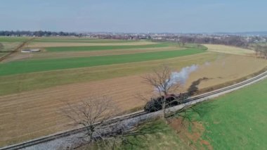 Ronks, Pennsylvania, ABD, 11 Mart 2022 - Bir buhar treni yemyeşil alanlarda ve açık kırsal alanlarda dolaşırken, tek başına, dumanı dalgalanan raylar boyunca tıkınır. - Evet. Yüksek kalite 4k görüntü
