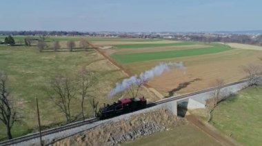Kaliteli bir buhar treni, yemyeşil tarlalarda ve açık kırlarda dolaşırken tek başına dumanı dalgalanan raylar boyunca tıkınır. Yüksek kalite 4k görüntü
