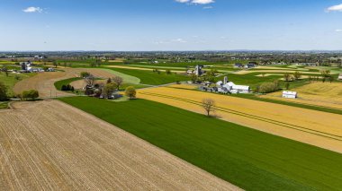 Bereketli yeşil ve altın çayırların geniş bir manzarası araziye yayılıyor, açık bir günde hepsi güneş ışığıyla yıkanmış çiftlik binaları ve ağaçlarla birlikte..