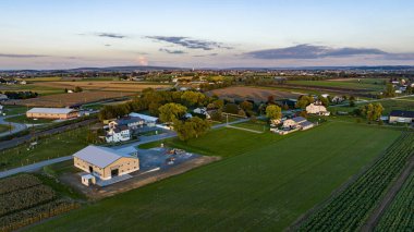 Geniş bir hava manzarası günbatımında Pennsylvania kırsalının dingin güzelliğini yakalar, tarım arazileri, ağaçlar ve yerleşim alanları sergilenir. Titreşimli manzara, kır yaşamının sükunetini yansıtıyor..