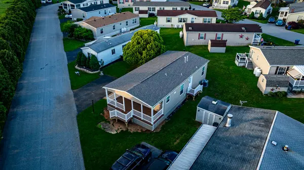 Mobil konut, üretim, prefabrik, bir sürü evi ve ağacı olan Home Park. Evler beyaz, ağaçlar yeşil. Gökyüzü bulutlu ve evler yayılmış.