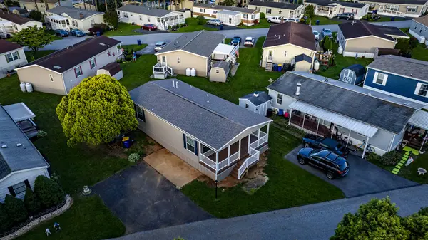 Mobil konut, üretim, prefabrik, bir sürü evi ve ağacı olan Home Park. Evler beyaz, ağaçlar yeşil. Gökyüzü bulutlu ve evler yayılmış.