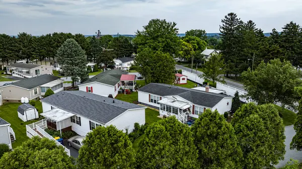 Mobil konut, üretim, prefabrik, bir sürü evi ve ağacı olan Home Park. Evler beyaz, ağaçlar yeşil. Gökyüzü bulutlu ve evler yayılmış.