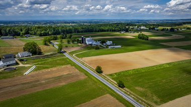 Geniş tarım alanları yeşillik ve kahverengi toprağın karışımını sergileyerek araziye hükmediyor..