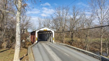 Büyüleyici bir köprü kırsal alanda sakin bir yol boyunca uzanır. Güneşli kış günü çıplak ağaçları vurguluyor, bu sahneyi resim gibi ve huzurlu yapıyor..