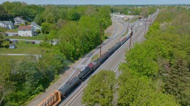 Cennet, Pennsylvania, 17 Mayıs 2023 - Buharlı motor, sakin kırsal bir ortamda, canlı yeşilliklerle çevrili raylar boyunca yük vagonlarını hareket ettiriyor..