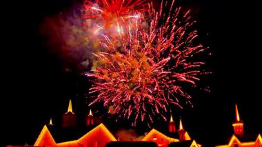 Canlı bir havai fişek gösterisi izleyicileri cezbediyor. Renkli patlamalar büyüleyici tarihi bir kasabanın üzerindeki karanlık gökyüzünü aydınlatıyor ve yerel bir kutlama sırasında şenlikli bir atmosfer yaratıyor..