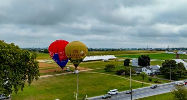 Pensilvanya 'da Kuş, 13 Eylül 2024 - İki renkli sıcak hava balonu, tarlalar ve çiftliklerle çevrili kırsal bir alanda havalanmaya hazırlanıyor. Etkinlik güzelliği gözler önüne seriyor