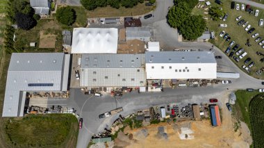 Hava perspektifi geniş bir tarımsal tesisi hareketli bir şekilde yakalar. Yeşil tarlalar ve inşaat alanlarıyla çevrili kamyonlar ve ekipmanlar görülebilir durumda..