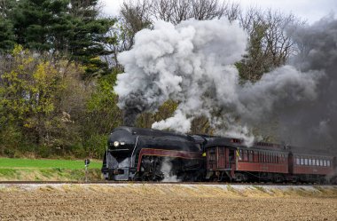Antika bir buhar lokomotifi kırsal bölgelerde dolaşarak kıtır sonbahar havasına siyah duman bulutları salıyor. Renkli ağaçlar, tren ilerlerken nostaljiyi çağrıştıran bir zemin sağlar..