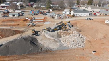 Gordonville, Pennsylvania, 10 Mart 2025 - Ağır makineler kırsal bir yerdeki bir inşaat alanında büyük miktarlarda ezilmiş taş ve toprak işliyor. İş ilerledikçe kamyonlar malzemeleri hareket ettirir.