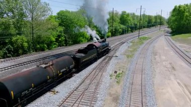 Cennet, Pennsylvania, 5 Mayıs 2023 - Temiz bir bahar gününde, verimli yeşilliklerle çevrili tarihi bir buharlı yük treni tren rayları boyunca seyahat eder. Güçlü lokomotife tanık olun..