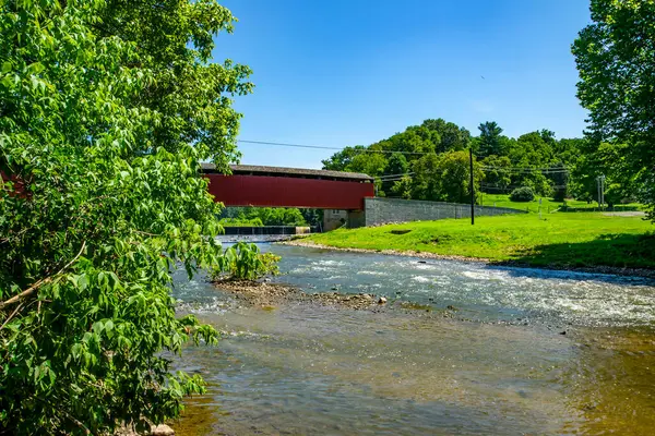 Manzaralı bir manzara, güneşli bir günde hafifçe akan bir nehri kaplayan üstü kapalı bir köprüyü gözler önüne seriyor. Bölge canlı ağaçlar ve yemyeşil otlarla çevrili. Huzuru davet ediyorlar..