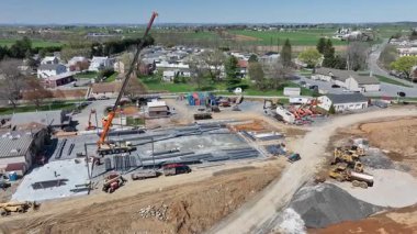 Gordonville, Pennsylvania, 9 Nisan 2025 - Ağır makinelerin kullanıldığı bir kırsal alanda inşaat çalışmaları devam ediyor. Bir vinç araçlar yol alırken malzeme taşımada yardımcı olur