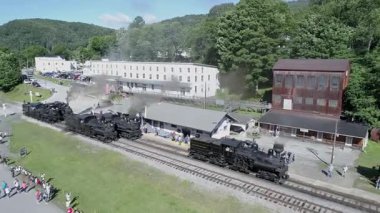 Cass, Batı Virginia, 18 Haziran 2022 - Ziyaretçiler yemyeşil yeşilliklerle çevrili tarihi bir tren istasyonunda buharlı lokomotiflerin seslerinin ve görüntülerinin keyfini çıkarıyorlar. Atmosfer çok canlı ve nostaljik.