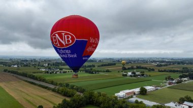 Pensilvanya Kuşu, 13 Eylül 2024 Pennsylvania 'nın yemyeşil alanları üzerinde renkli sıcak hava balonları zarifçe süzülüyor. Bulutlu gökyüzü sakin bir atmosfer yaratıyor. İnsanlar benzersizliğin tadını çıkarıyor.