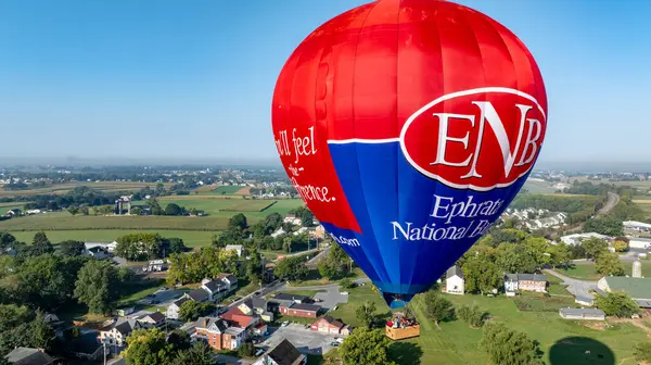 Canlı bir sıcak hava balonu, Eyfata Ulusal Parkı 'nın üzerinde süzülerek güzel yeşil manzarayı gözler önüne seriyor. Bird in Hand, Pennsylvania, 13 Eylül 2024 -