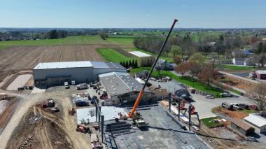 Pensilvanya kırsalında vinç ve çelik kirişli bir inşaat alanının havadan çekimleri endüstriyel aktiviteleri canlı renklerle, zengin detaylı sinematik kalitede gösteriyor.