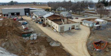 Ağır makineler ve inşaat malzemeleri, tadilat yapılan bir kırsal araziye saçılmış durumda..