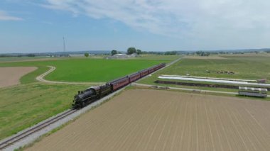 Ronks, Pensilvanya, 29 Mayıs 2023 - Bir buharlı yolcu treni, açık mavi bir gökyüzü altında seyahat ederek kırsal güzelliğin büyüleyici atmosferik görüntülerini sergiliyor.