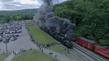 Cass, Batı Virginia, 18 Haziran 2022 - Büyük bir kalabalık çok sayıda buhar treninin büyük duman bulutlarını serbest bırakmasını izlemek için toplandı. Olay, manzaralı dağlarda gerçekleşerek nostaljik bir atmosfer yarattı.