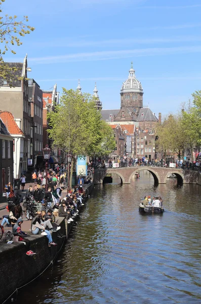 アムステルダム オランダ 4月2022 アムステルダムの運河とアムステルダムの銀行に座っている観光客 オランダ16 4月2022 — ストック写真