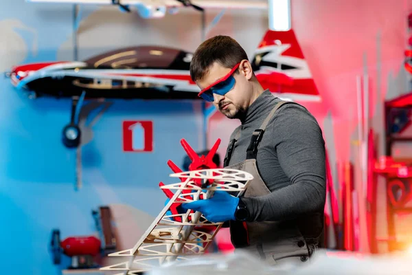 stock image Young male engineer or technician working on drone details in lab. Aircraft capable of GPS surveillance. Carbon