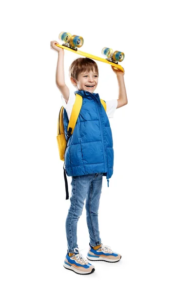 照片上 一个快乐的金发碧眼的男孩 头顶着黄色的长板 背景是白色的 回学校去 免版税图库图片