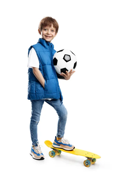 一个笑容满面的小男孩背负着白底足球的照片 回学校去 图库照片