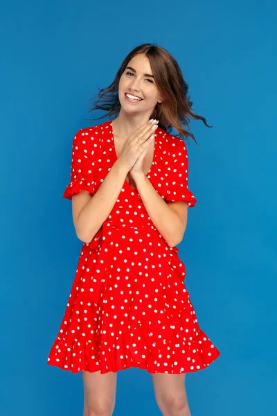 魅力的な若いです女性とともに明るい笑顔で赤いドレス気持ち幸せ上の青の背景 — ストック写真