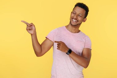 Gülümseyen Afrikalı Amerikalı genç adam sarı arka planı işaret ediyor. Fikir kavramı