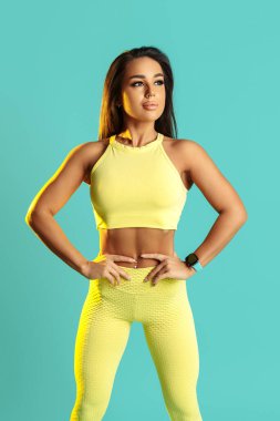 Atletik genç esmer kadın mavi arka planda fonksiyonel egzersizler yapıyor. Güç ve motivasyon kavramı