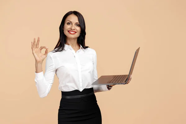 Stock image Attractive young modern business woman with notebook show ok gesture over beige background