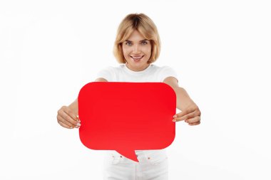 Beyaz arka planda kırmızı boş konuşma balonu tutan çekici sarışın kadın.