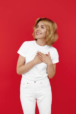 Beyaz giysili neşeli sarışın kadın kırmızı arka planda el ele tutuşuyor.
