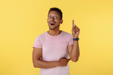 Komik Afrikalı Amerikalı genç adam sarı arka planı işaret ediyor. Fikir kavramı