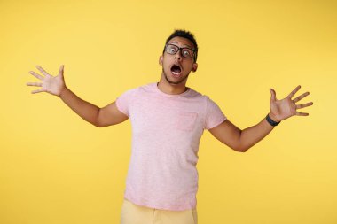 Şaşırtıcı başarılı Afrikalı Amerikalı genç adam zaferini sarı arka planda elleri açık kutluyor.