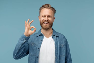 Sakallı hippi, kot gömlekli sarışın adam mavi arka planda iyi niyet gösterisi gösteriyor..