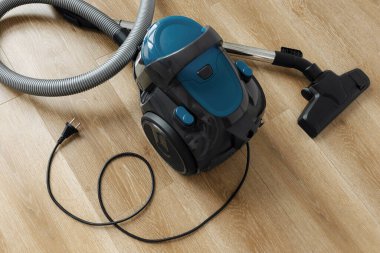 Oturma odasındaki ahşap zeminde modern mavi elektrikli süpürge. Kalp Şekli. Temiz Ev Konsepti