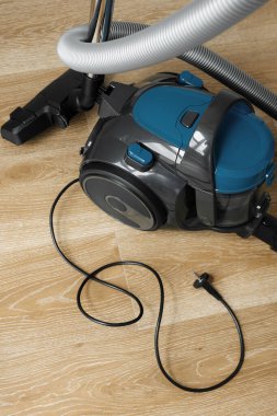 Oturma odasındaki ahşap zeminde modern mavi elektrikli süpürge. Kalp Şekli. Temiz Ev Konsepti