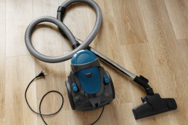 Oturma odasındaki ahşap zeminde modern mavi elektrikli süpürge. Kalp Şekli. Temiz Ev Konsepti