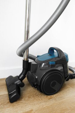 Oturma odasındaki ahşap zeminde modern mavi elektrikli süpürge. Kalp Şekli. Temiz Ev Konsepti